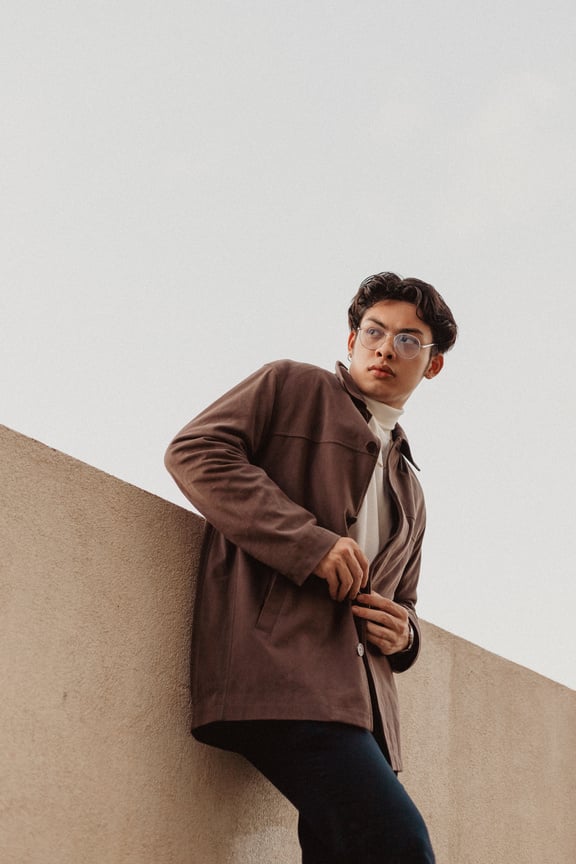 Young Man in Brown Jacket Standing against the Wall