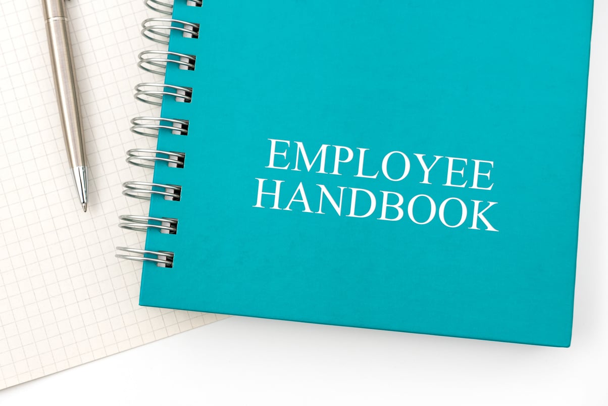 Employee Handbook or manual with a pen and paper on a white table in an office.